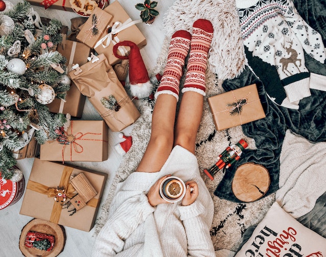 Christmas Gift Ideas for coworkers under $10 laid in a carpet with woman legs and a cup of hot beverage.