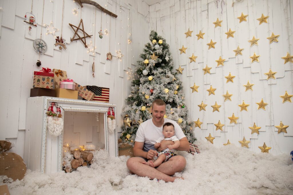 Cheap stocking stuffer ideas under $5. A man carrying a baby in front of a Christmas tree