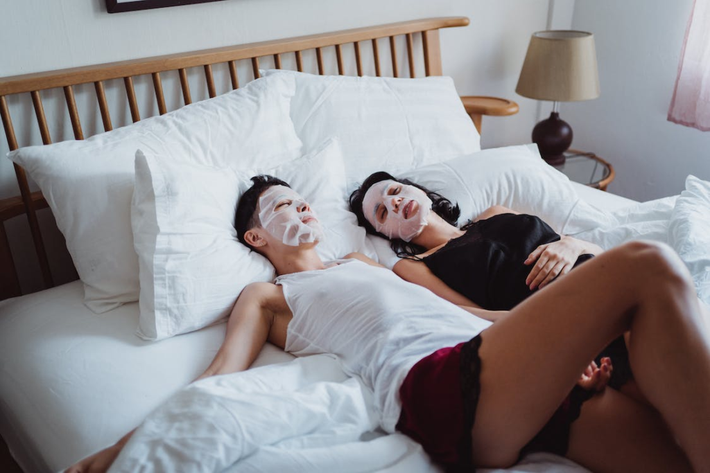 Couples on face mask lying in bed as they do skin care for indoor winter activities for couples
