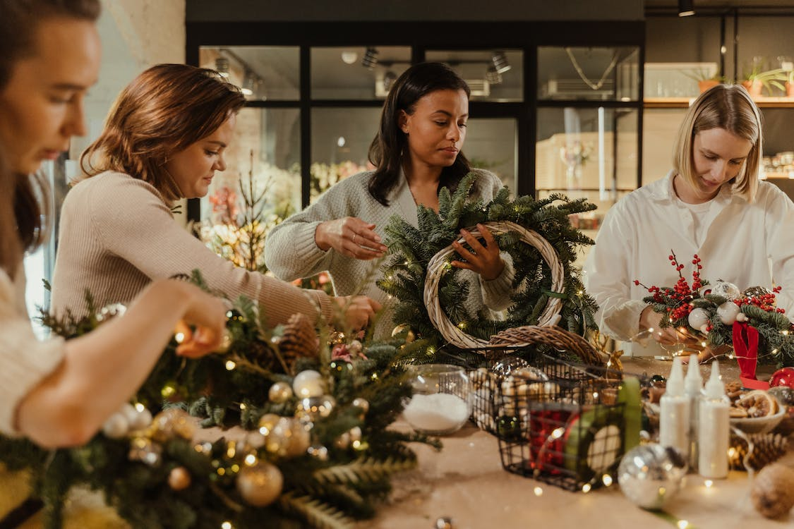 Friends making Christmas wreaths at home as a winter crafts for adults
