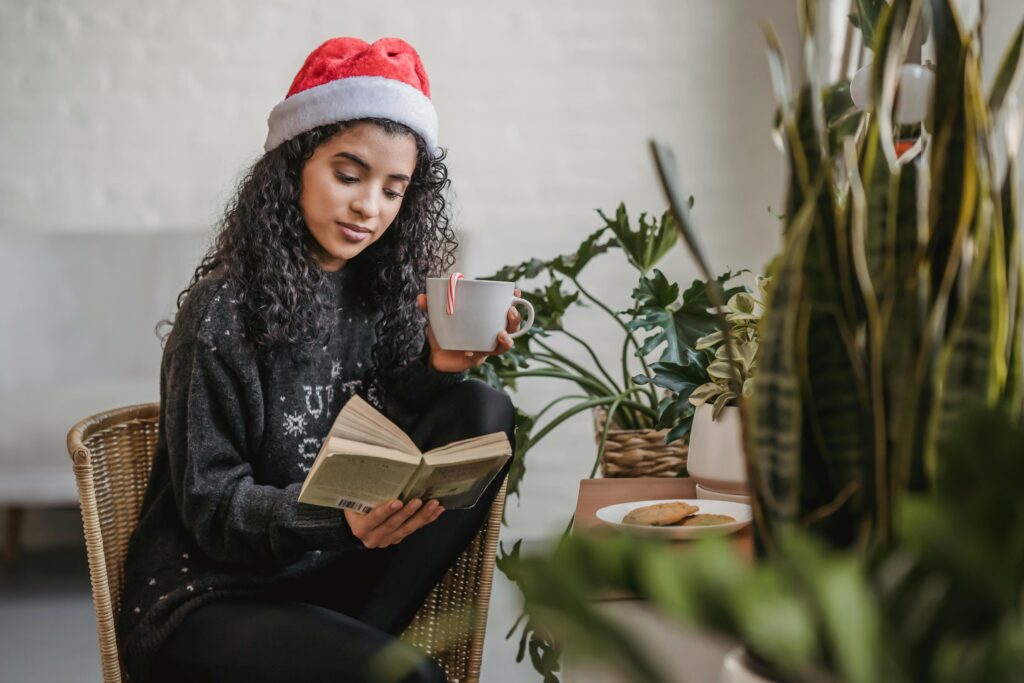 A woman reading a book while sipping a hot cocoa as an indoor winter activities for adults.