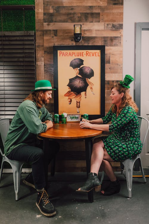 A man in a green dress shirt and a woman in a green shirt face to face on the table playing games as a St Patrick's Day office ideas.