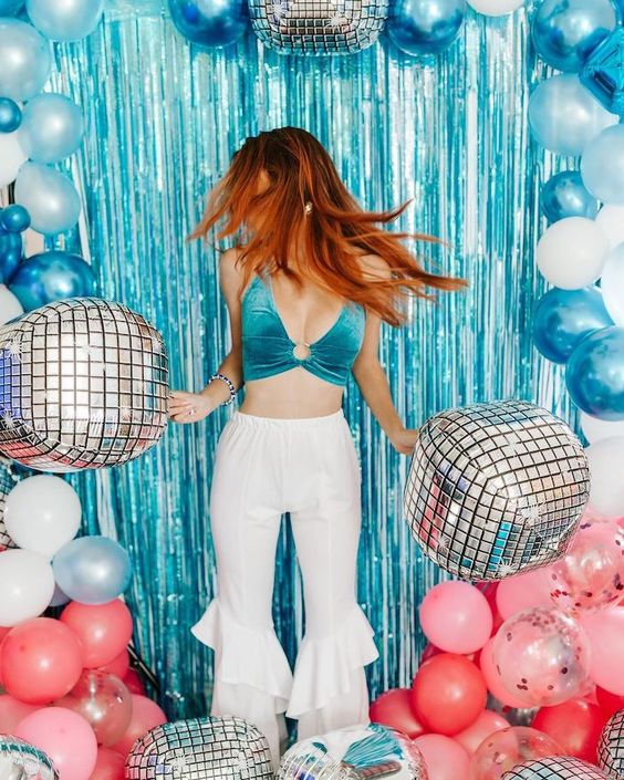 Mamma Mia party ideas for a photobooth a blue glittery backdrop with balloons and disco balls.